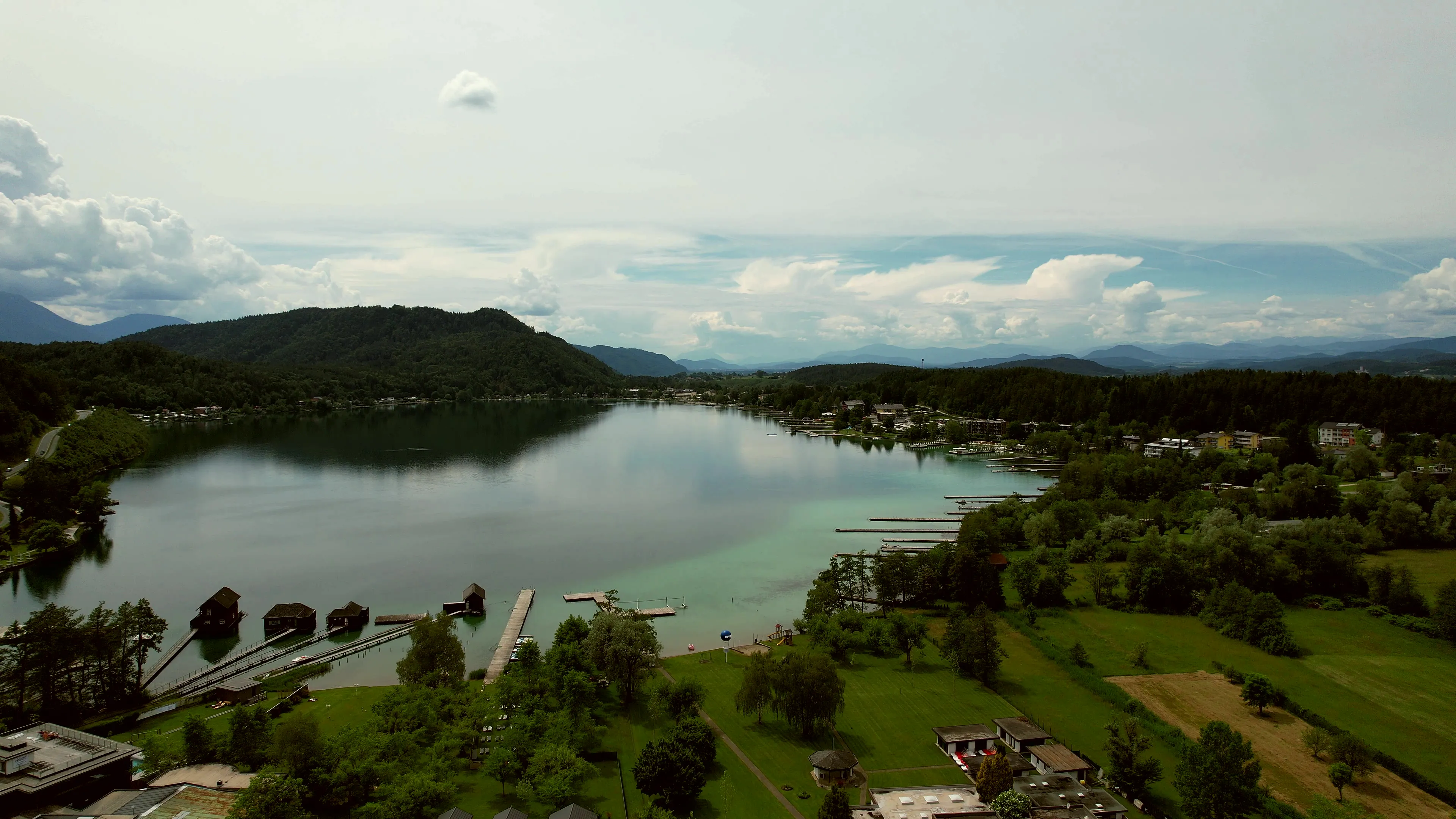 Luftaufnahme des Klopeiner Sees mit Stegen, Bootshäusern und dem Areal der Therme